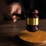 A gavel striking a sound block, symbolizing justice and legal authority in a courtroom setting.
